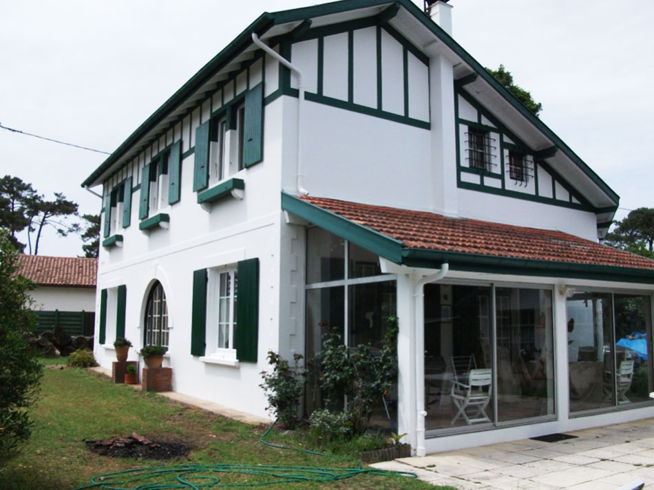 Maison blanche avec volets verts et véranda