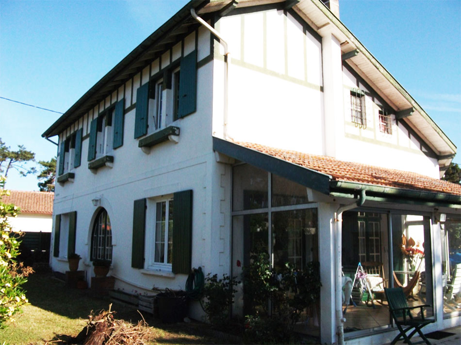 Maison blanche avec volets verts et véranda