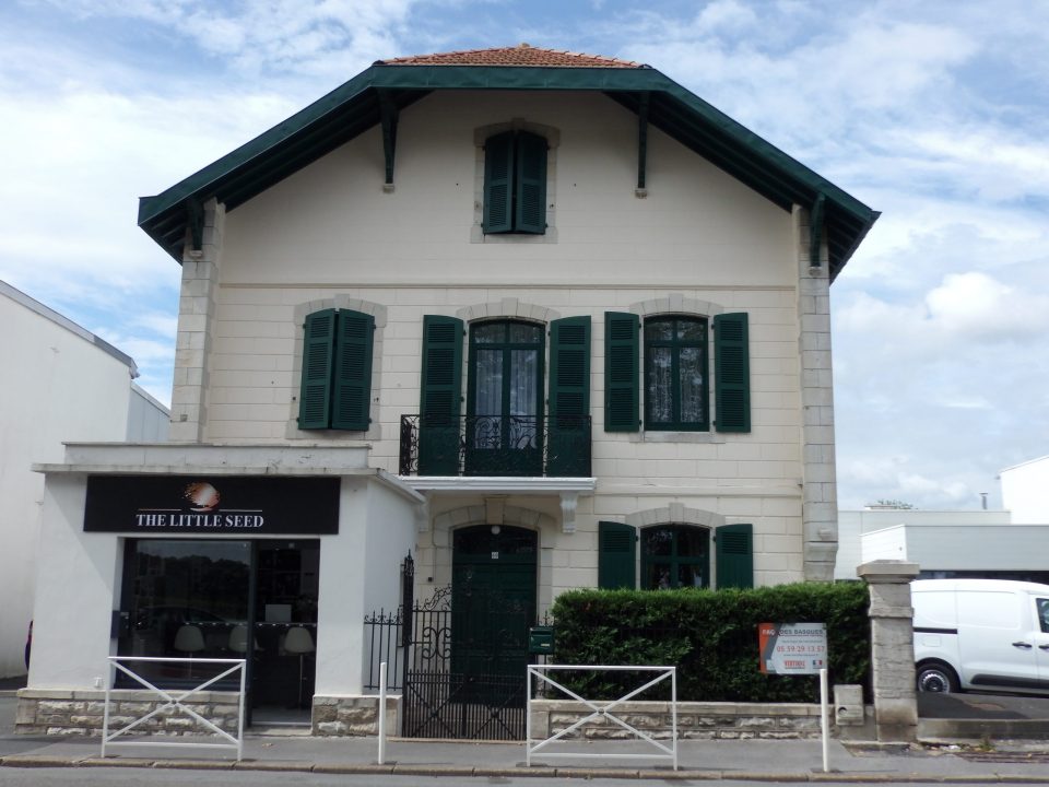 Maison blanche avec volets verts, boutique au rez-de-chaussée