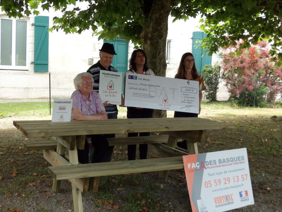 Personnes tenant un chèque sous un arbre