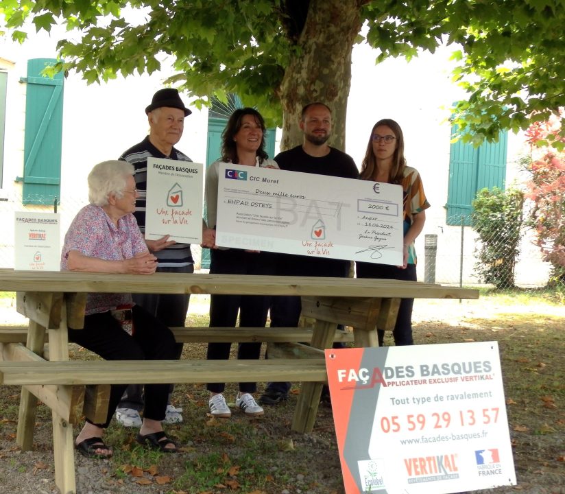 Personnes tenant un chèque sous un arbre.