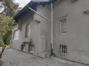 Maison grise avec fenêtres en arc et grilles