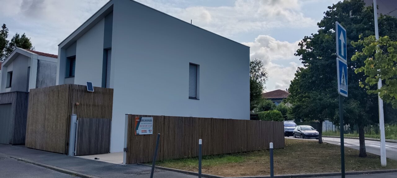 Maison moderne avec clôture en bois et panneau de vente