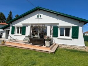 Maison blanche avec volets verts et terrasse en bois