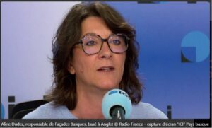 Femme portant des lunettes parle dans un microphone.